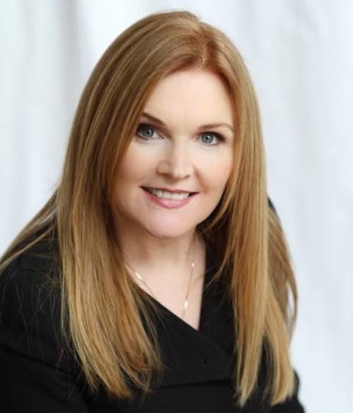 web1_Danica-Kombol Woman with red hair smiling at the camera.